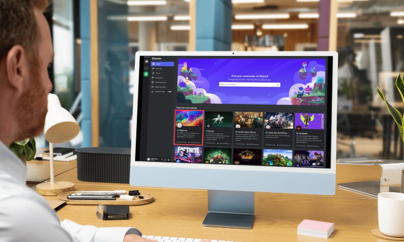 A man sits at a desk, focused on a computer screen in front of him