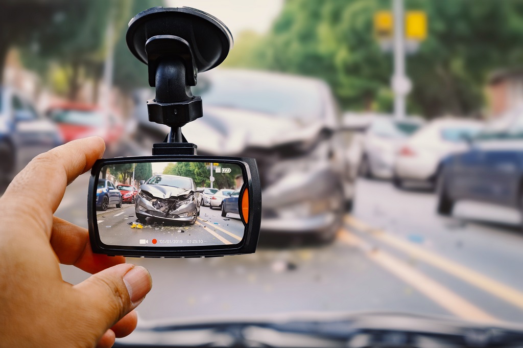 Hand holding dash cam displaying recorded car accident footage for review