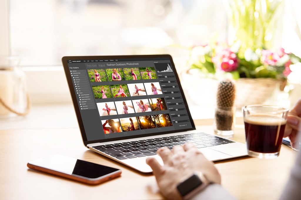 Laptop screen displaying photo editing software with images in organized workflow